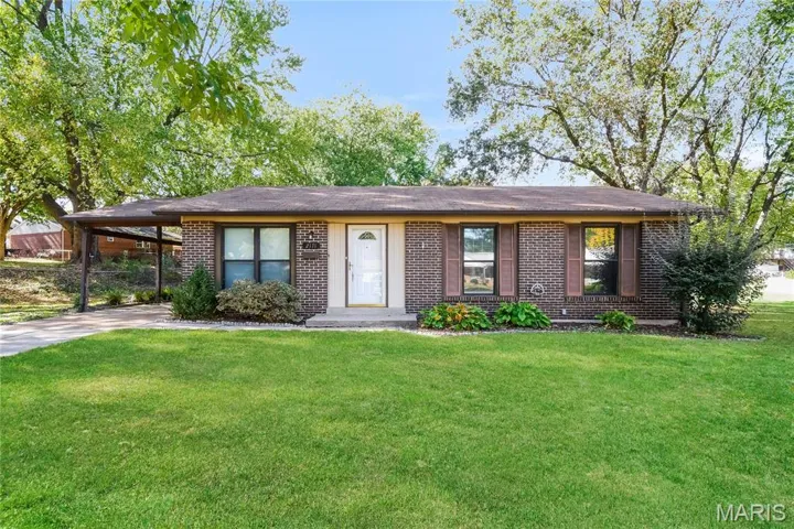 Single story home with a front yard, brick siding, a carport, concrete driveway, and a shingled roof