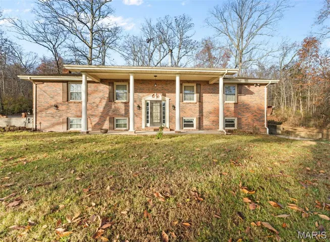 View of front of property with brick siding, covered porch, and a front yard