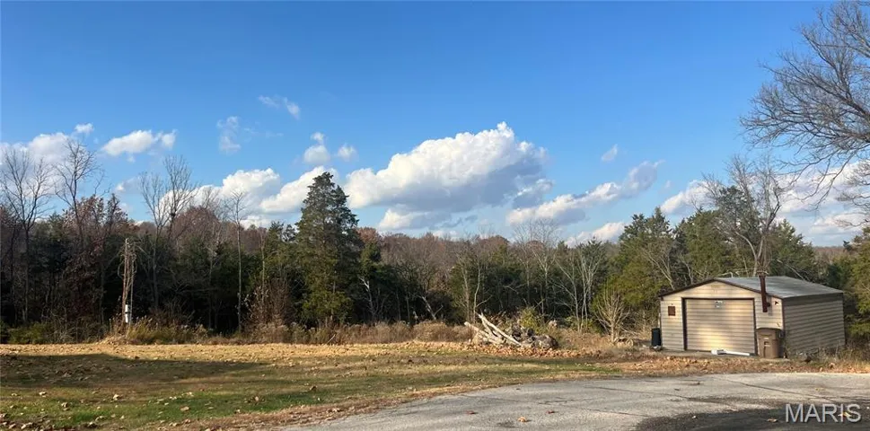 View of asphalt road featuring a wooded view