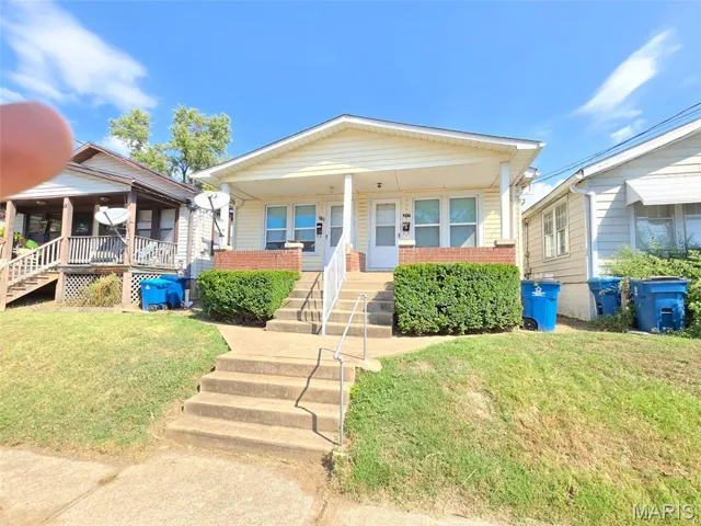 View of front facade with a front lawn, brick siding, and a porch