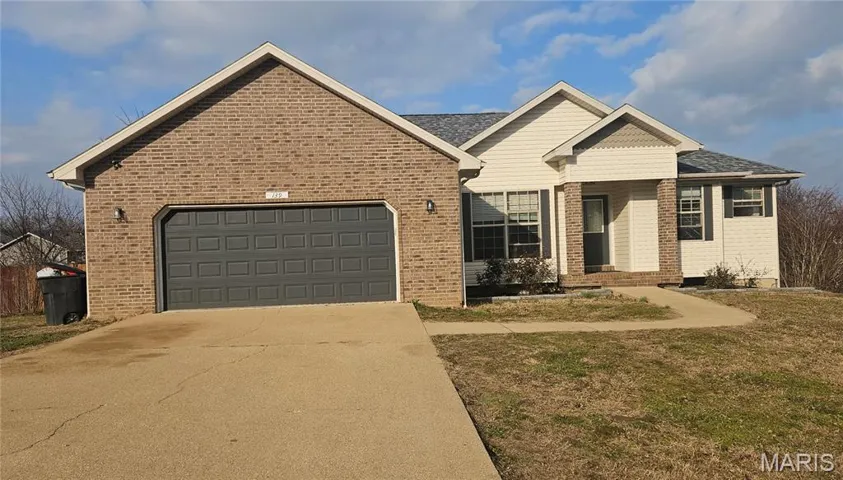 Ranch-style home featuring a front lawn, concrete driveway, an attached garage, brick siding, and a shingled roof