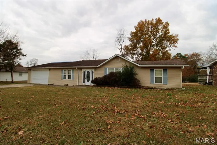 Ranch-style home with a front yard, driveway, and an attached garage