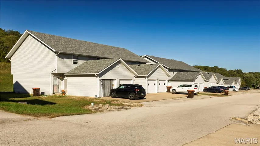 View of property exterior with roof with shingles, driveway, and a residential view