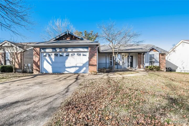 Single story home with brick siding, concrete driveway, covered porch, and an attached garage