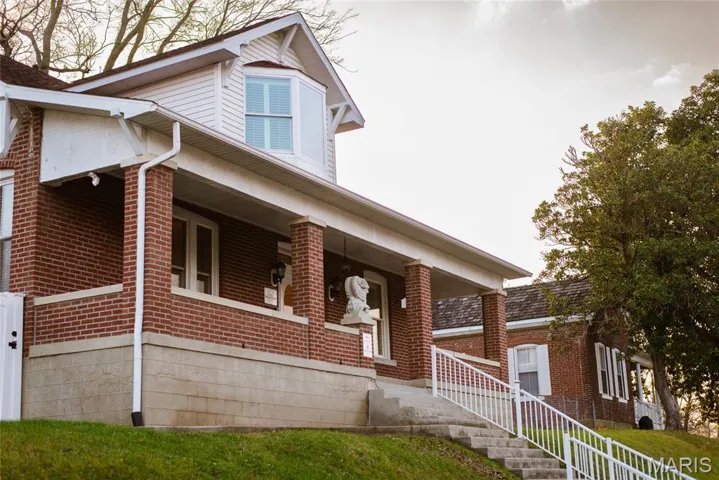 View of front facade featuring covered porch, brick siding, and a front lawn