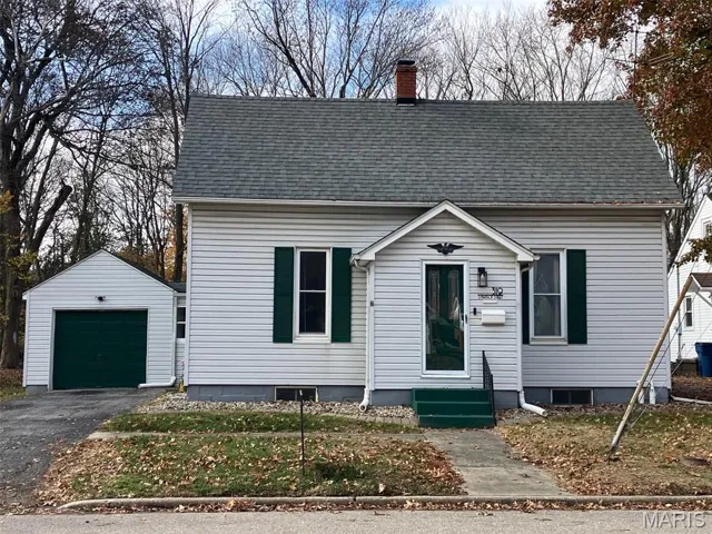 View of front of home featuring an outdoor structure, a shingled roof, driveway, a garage, and a chimney