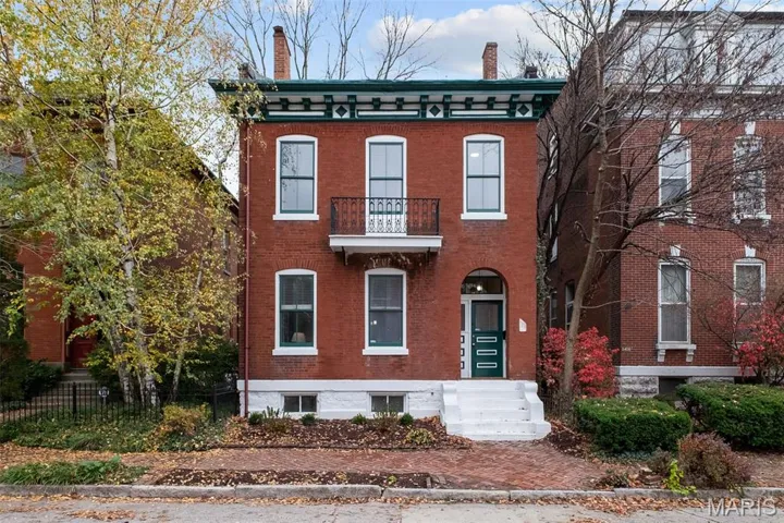 Italianate house with a balcony, a chimney, and brick siding