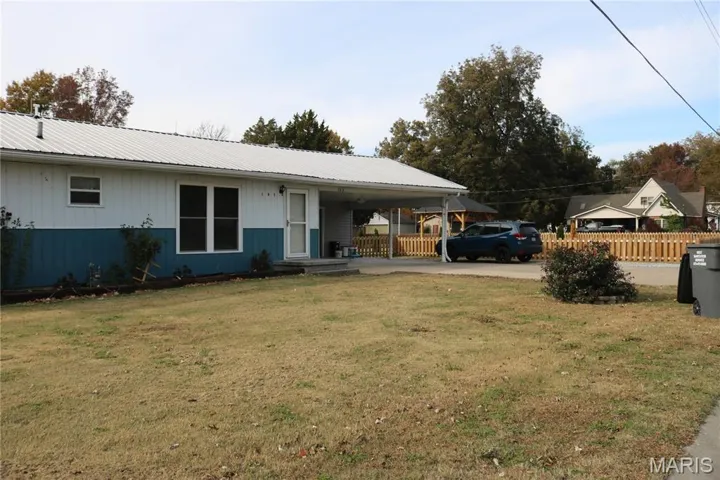 Ranch-style house featuring covered porch, concrete driveway, a metal roof, and a carport