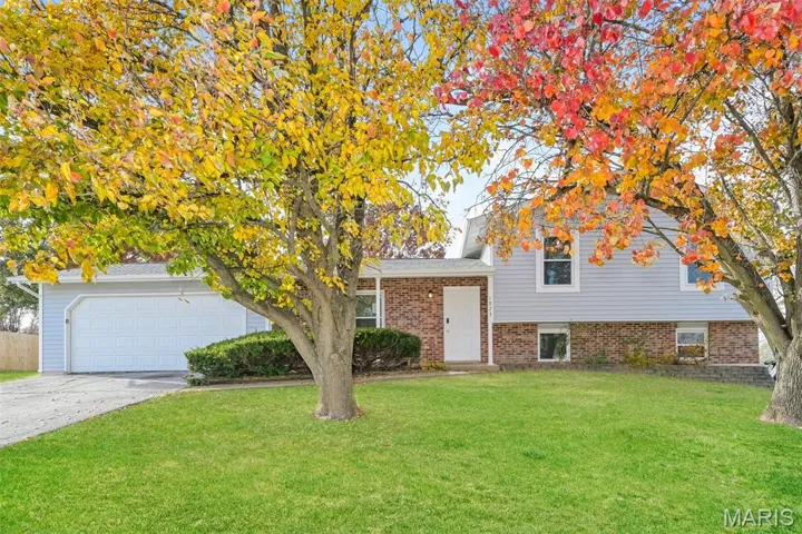 View of front of home featuring a front yard, concrete driveway, brick siding, and a garage