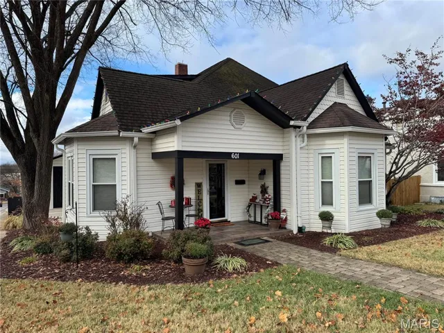 View of front of house featuring a porch, a front lawn, a shingled roof, and a chimney