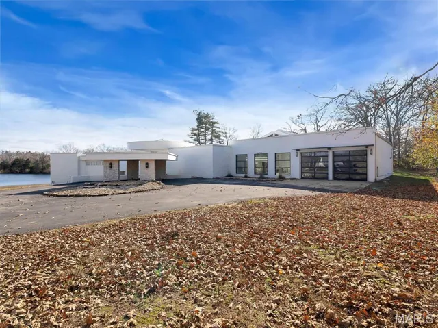 View of front of house with stucco siding, concrete driveway, and a garage