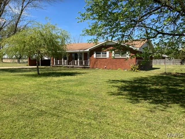 Back of property featuring covered porch and brick siding