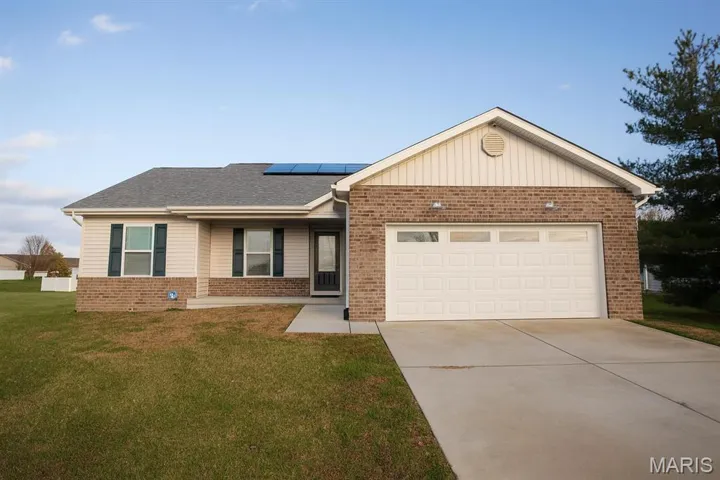 Ranch-style house featuring brick siding, solar panels, concrete driveway, covered porch, and a front yard