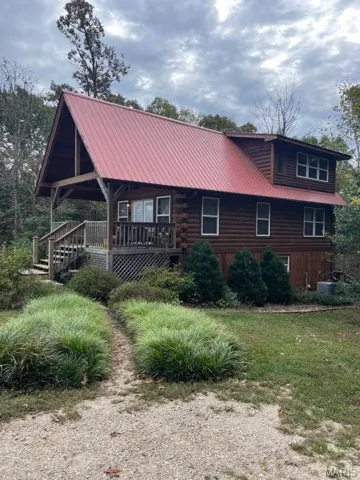 View of side of property with a metal roof, log siding, and stairway