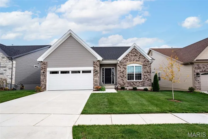 Single story home featuring brick siding, concrete driveway, a front yard, a garage, and roof with shingles
