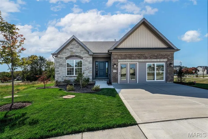 View of front of home featuring a front lawn, board and batten siding, stone siding, and concrete driveway