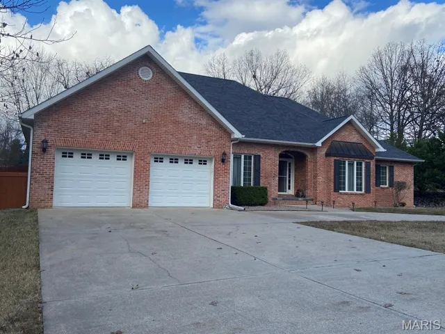 Ranch-style home featuring driveway, brick siding, and an attached garage