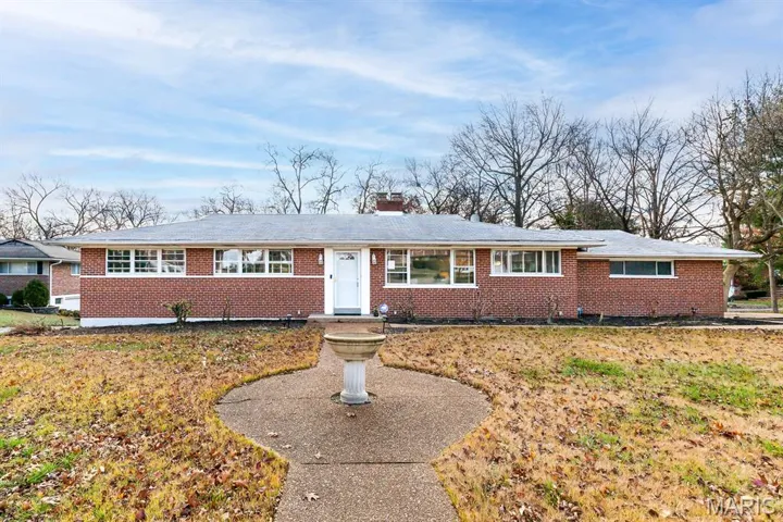 Ranch-style home featuring brick siding, a chimney, and a front yard