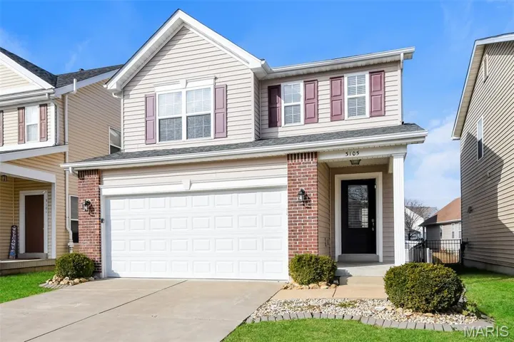 Traditional-style house featuring brick siding, concrete driveway, an attached garage, and a shingled roof