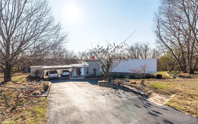 View of front facade with asphalt driveway, an attached carport, and stucco siding