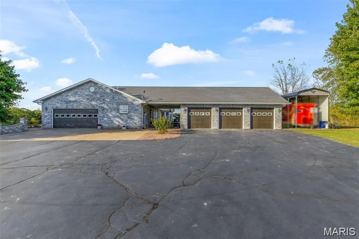 Ranch-style house with asphalt driveway, an attached garage, and stone siding