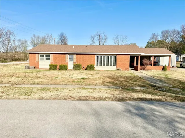 Ranch-style home featuring brick siding, a porch, and a front yard