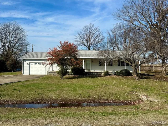 Ranch-style house with a front lawn, a porch, driveway, and an attached garage
