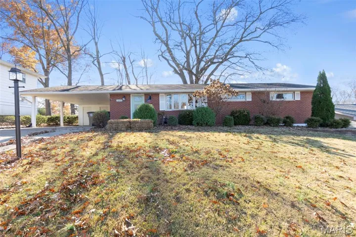Single story home featuring brick siding, driveway, a front lawn, and a carport