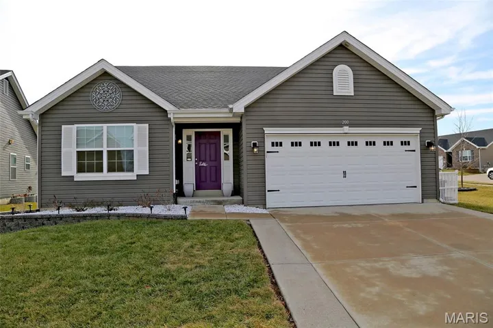 Ranch-style house featuring a front yard, concrete driveway, and an attached garage