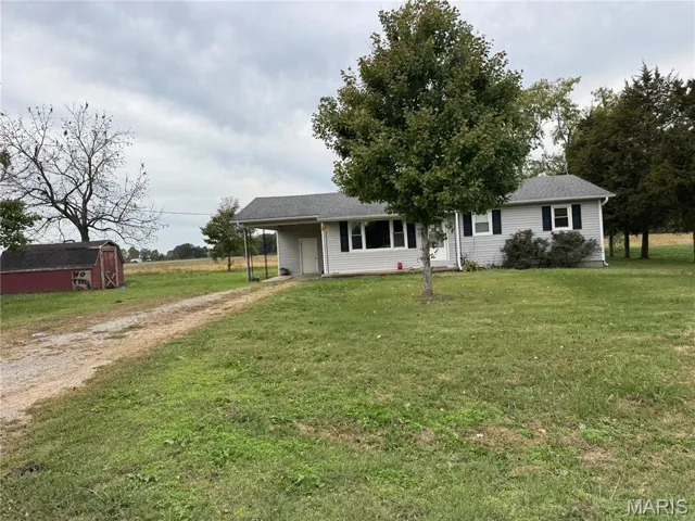 Ranch-style home with driveway, a front yard, and an outbuilding