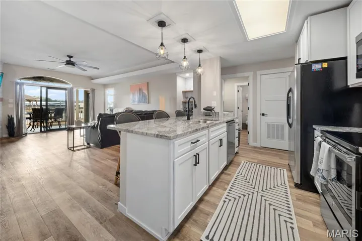 Kitchen with a breakfast bar, open floor plan, white cabinetry, and stainless steel appliances
