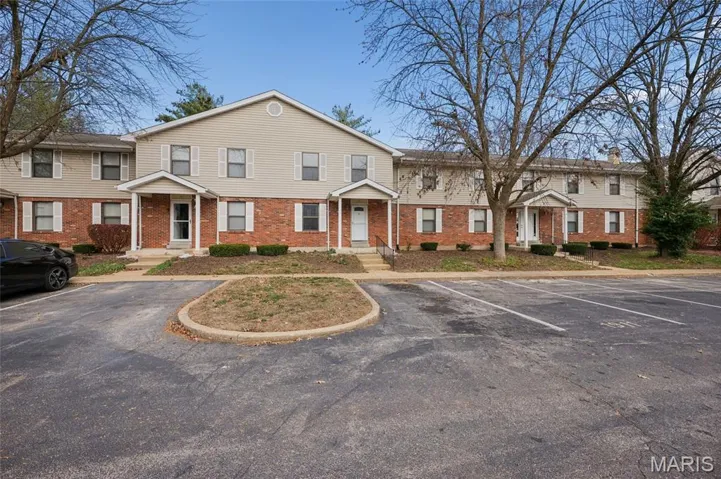 Colonial inspired home with brick siding and uncovered parking