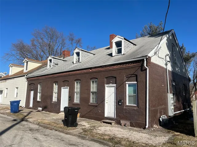 View of front of property featuring a chimney, brick siding, and a shingled roof