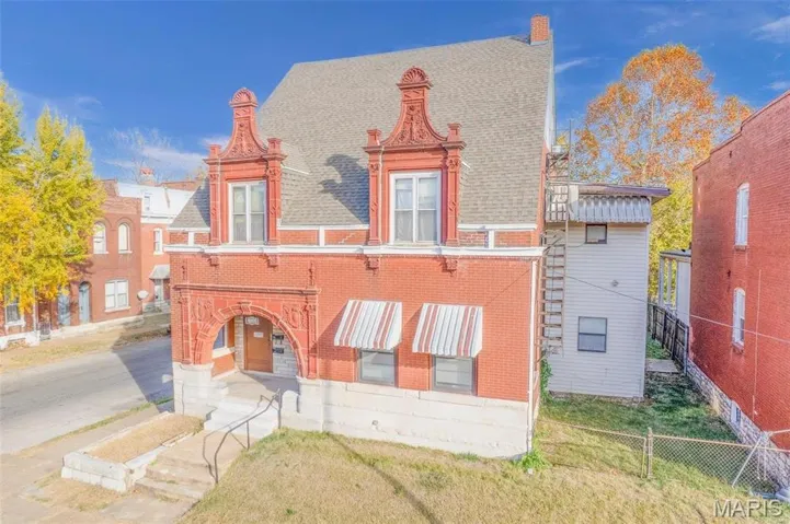 View of front of home featuring a shingled roof, a chimney, and brick siding