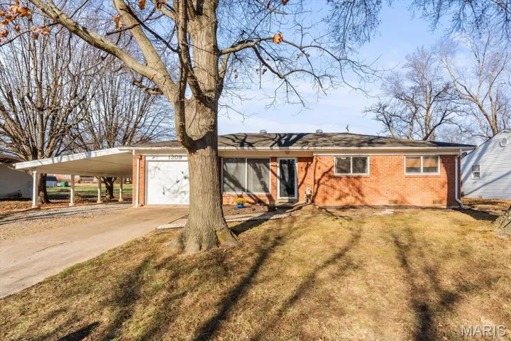 Single story home featuring brick siding, a front yard, concrete driveway, and an attached carport