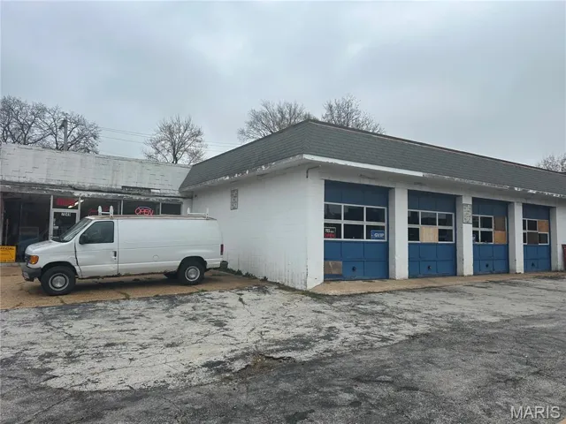 View of property exterior with concrete block siding and mansard roof