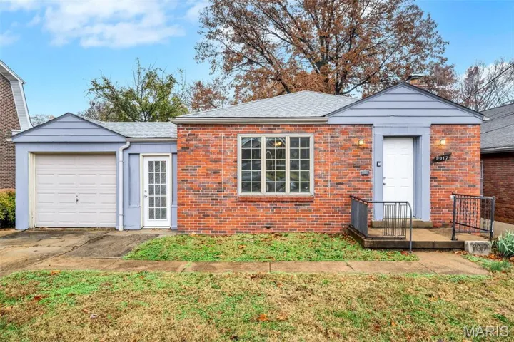 View of front facade with brick siding, a front yard, concrete driveway, and an attached garage