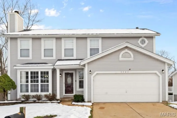 Traditional-style home with driveway, a chimney, and an attached garage