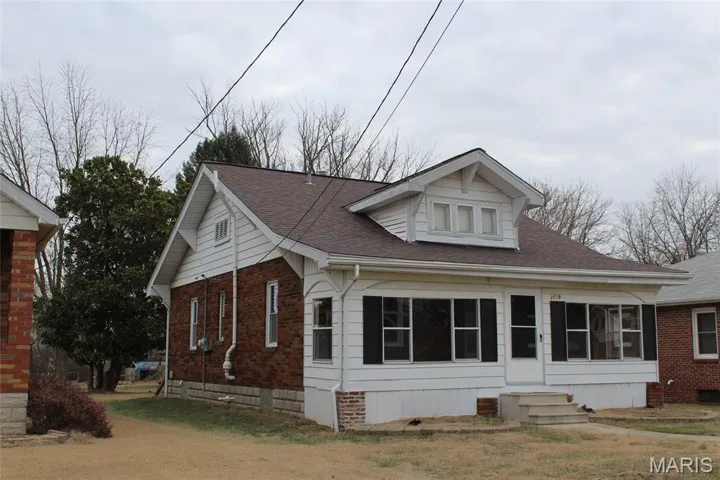 View of front of home with a sunroom, roof with shingles, brick siding, and entry steps