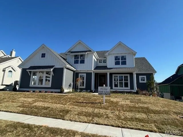 View of front of home with a porch, a front lawn, and board and batten siding