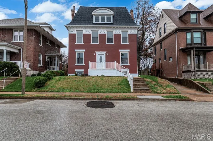 View of front of house featuring a chimney, a front lawn, roof with shingles, and brick siding