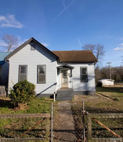View of front of home featuring a fenced front yard, a gate, and a shingled roof