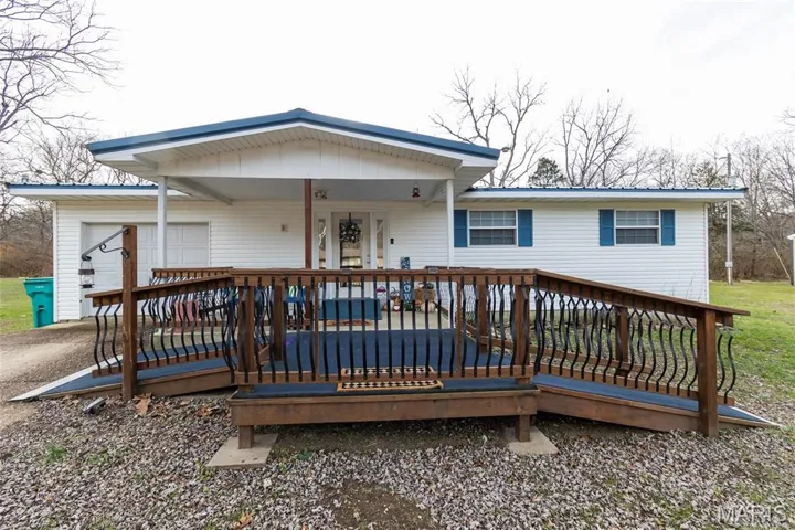 View of front facade featuring a wooden deck and an attached garage