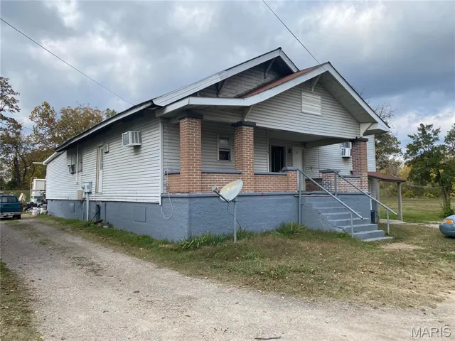 View of front facade featuring a porch, brick siding, and an AC wall unit