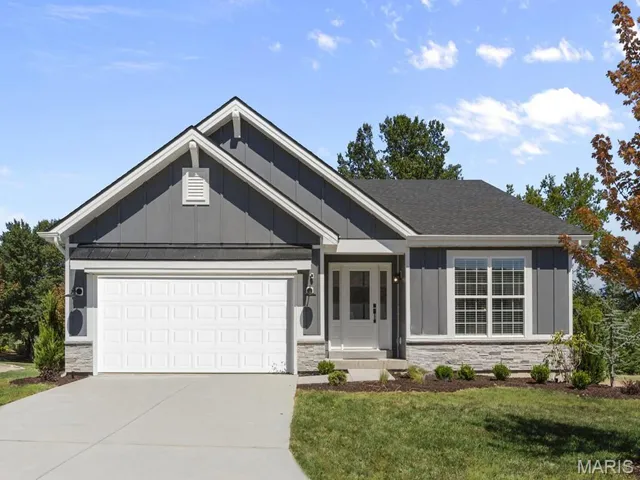 Single story home featuring board and batten siding, stone siding, concrete driveway, an attached garage, and a front yard