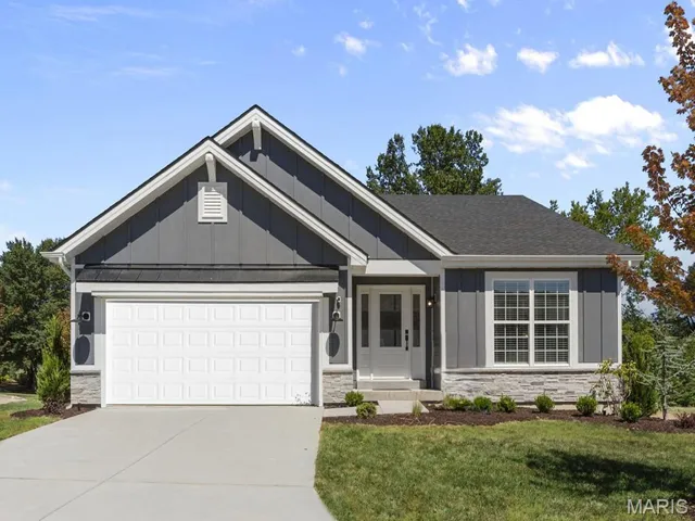Ranch-style house featuring board and batten siding, stone siding, and driveway