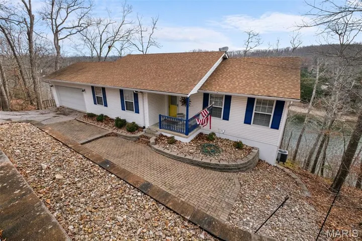 Ranch-style house with covered porch, roof with shingles, and driveway