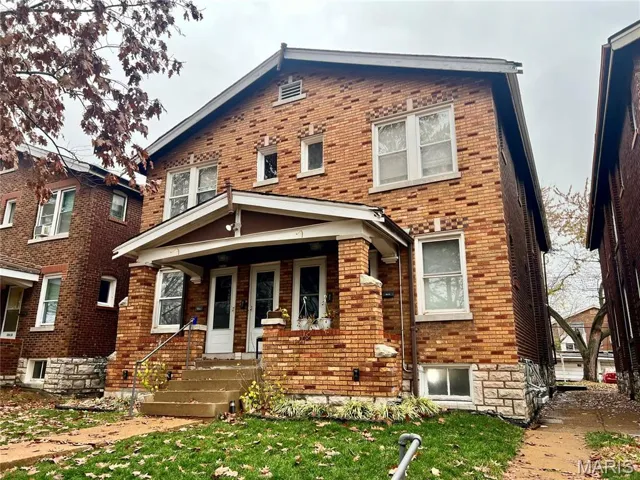 View of front of property featuring brick siding, a front yard, and covered porch