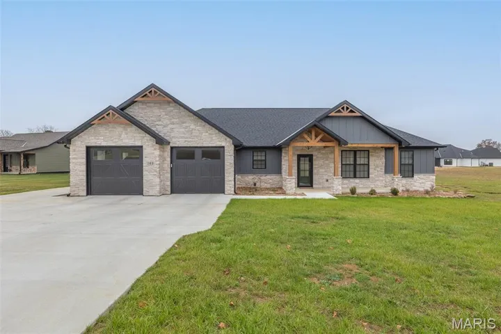 Modern inspired farmhouse with a front yard, a porch, stone siding, concrete driveway, and a garage