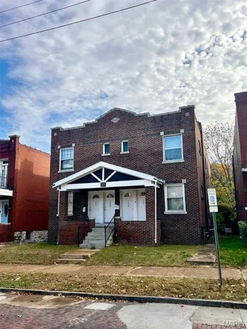 Traditional home featuring brick siding, covered porch, and a front yard